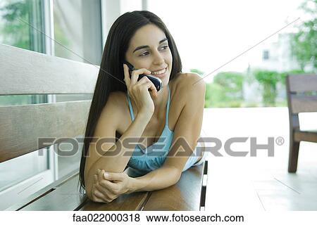 Young woman lying on bench, using cell phone View Large Photo Image Stock Photo - Young woman lying on bench, using cell phone. Fotosearch