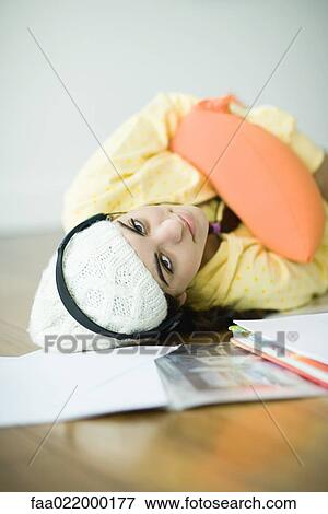 Young woman lying on floor listening to headphones, neglecting homework View Large Photo Image Stock Photo - Young woman lying on floor listening to headphones, neglecting homework. Fotosearch