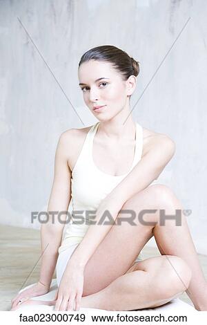Stock Photo - Young woman performing yoga pose, smiling at camera. Fotosearch