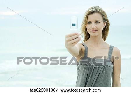 Young woman photographing self with camera phone, smiling, waist up View Large Photo Image Stock Photo - Young woman photographing self with camera phone, smiling, waist up. Fotosearch