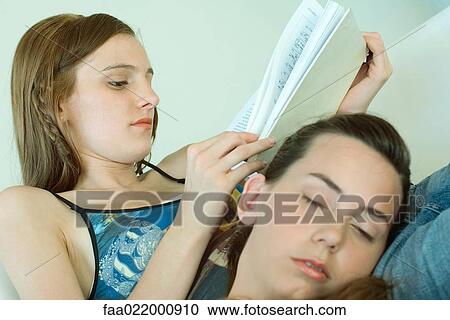 Young woman reading book, friend resting head on her lap, tilted view View Large Photo Image Stock Image - Young woman reading book, friend resting head on her lap, tilted view. Fotosearch