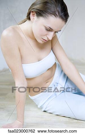 Young woman sitting on the ground, dressed in tubetop, looking down View Large Photo Image Stock Image - Young woman sitting on the ground, dressed in tubetop, looking down. Fotosearch