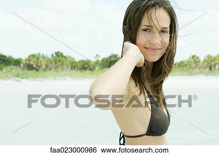 Young woman smiling at camera, wearing bikini, tousled hair, portrait View Large Photo Image Stock Photograph - Young woman smiling at camera, wearing bikini, tousled hair, portrait. Fotosearch