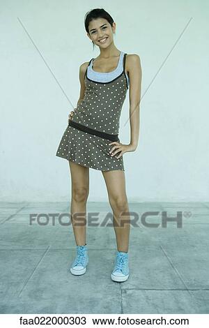 Young woman standing, smiling at camera, full length portrait View Large Photo Image Stock Image - Young woman standing, smiling at camera, full length portrait. Fotosearch