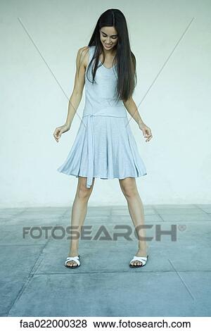 Young woman standing, wearing dress, looking down, full length portrait View Large Photo Image Stock Photo - Young woman standing, wearing dress, looking down, full length portrait. Fotosearch