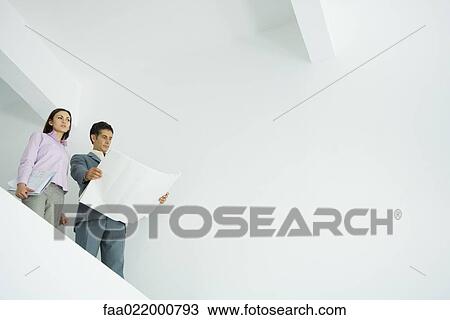 Young woman standing with architect, looking over bare interior View Large Photo Image Stock Image - Young woman standing with architect, looking over bare interior. Fotosearch