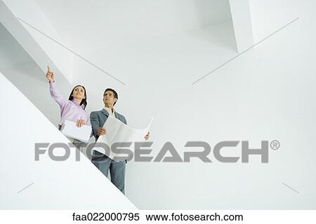 Young woman standing with architect, pointing out of frame, low angle view View Large Photo Image Stock Photography - Young woman standing with architect, pointing out of frame, low angle view. Fotosearch