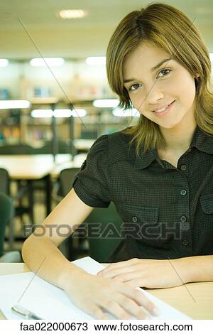 Young woman studying in university library, smiling at camera View Large Photo Image Stock Image - Young woman studying in university library, smiling at camera. Fotosearch
