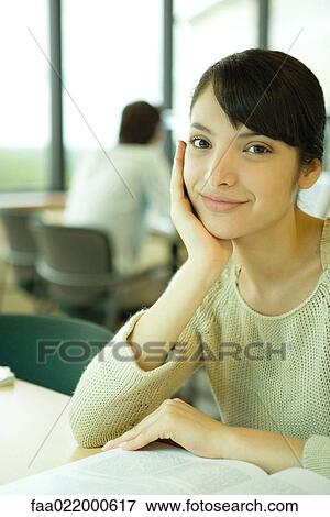 Young woman studying in university library, smiling at camera View Large Photo Image Stock Photo - Young woman studying in university library, smiling at camera. Fotosearch