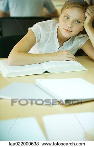 Young woman studying in university library, leaning on book and looking away View Large Photo Image Stock Photo - Young woman studying in university library, leaning on book and looking away. Fotosearch