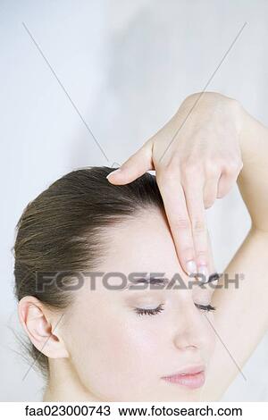 Stock Image - Young woman touching forehead, eyes closed, cropped view. Fotosearch