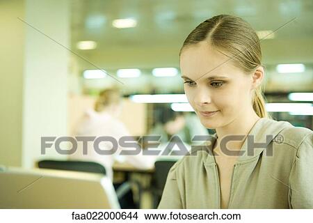 Young woman using laptop in library View Large Photo Image Picture - Young woman using laptop in library. Fotosearch