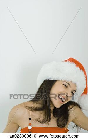 Young woman wearing Santa hat, smiling at camera, portrait View Large Photo Image Stock Image - Young woman wearing Santa hat, smiling at camera, portrait. Fotosearch