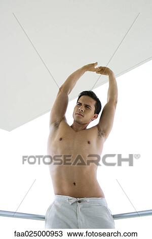 Barechested young man stretching arms over head, low angle view View Large Photo Image Stock Image - Barechested young man stretching arms over head, low angle view. Fotosearch