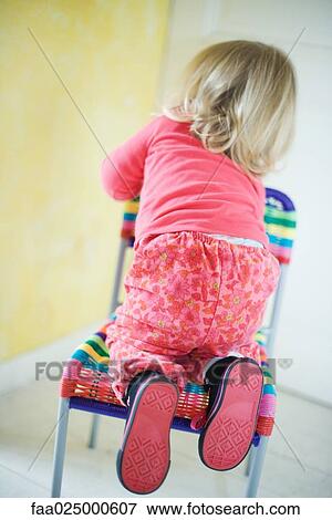 Blonde toddler girl climbing on chair, rear view View Large Photo Image Stock Photo - Blonde toddler girl climbing on chair, rear view. Fotosearch