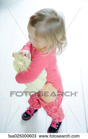 Blonde toddler girl holding baby doll upside down View Large Photo Image Stock Image - Blonde toddler girl holding baby doll upside down. Fotosearch