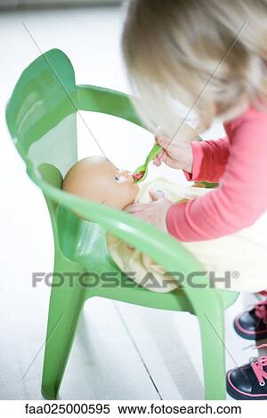 Blonde toddler girl pretending to feed baby doll View Large Photo Image Stock Photography - Blonde toddler girl pretending to feed baby doll. Fotosearch