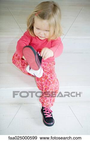 Blonde toddler girl putting on shoes, full length View Large Photo Image Stock Photo - Blonde toddler girl putting on shoes, full length. Fotosearch