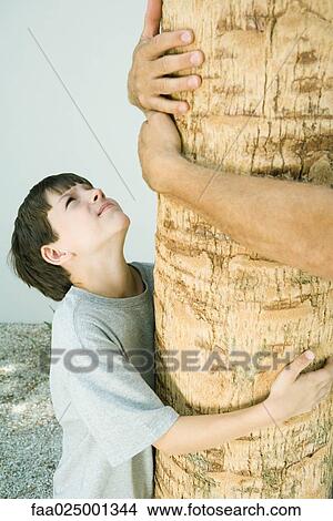 Boy and man hugging tree, cropped view View Large Photo Image Picture - Boy and man hugging tree, cropped view. Fotosearch
