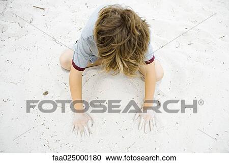 Boy crouching in sand, playing, high angle view View Large Photo Image Stock Image - Boy crouching in sand, playing, high angle view. Fotosearch