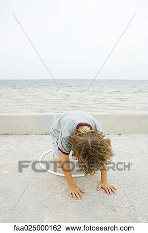 Boy crouching on all fours, playing with plastic hoop, head down View Large Photo Image Stock Image - Boy crouching on all fours, playing with plastic hoop, head down. Fotosearch
