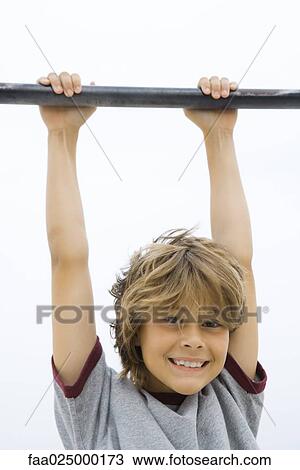 Boy hanging from metal bar, smiling at camera, portrait View Large Photo Image Stock Image - Boy hanging from metal bar, smiling at camera, portrait. Fotosearch