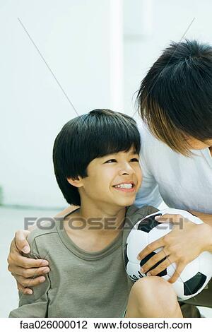 Boy holding soccer ball, smiling at father, portrait View Large Photo Image Stock Image - Boy holding soccer ball, smiling at father, portrait. Fotosearch