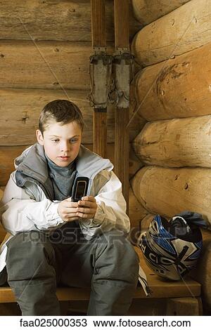 Boy in ski gear sitting, using cell phone View Large Photo Image Stock Image - Boy in ski gear sitting, using cell phone. Fotosearch