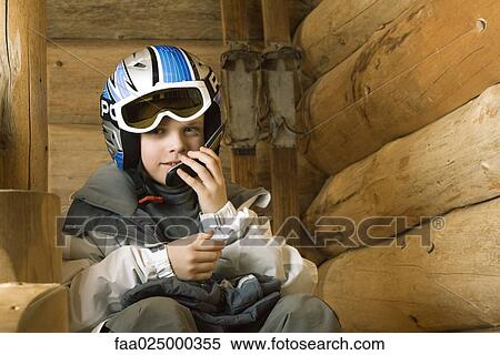 Boy in ski gear sitting, using cell phone View Large Photo Image Stock Photography - Boy in ski gear sitting, using cell phone. Fotosearch