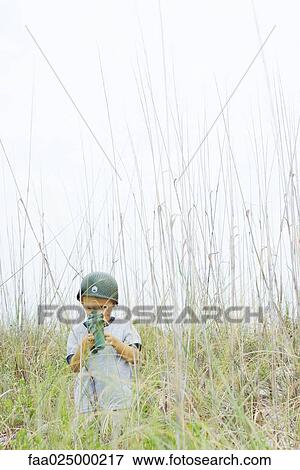 Boy in tall grass, aiming toy gun, looking at camera View Large Photo Image Stock Photo - Boy in tall grass, aiming toy gun, looking at camera. Fotosearch