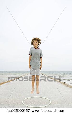 Boy jumping over plastic hoop at the beach, smiling at camera View Large Photo Image Stock Photo - Boy jumping over plastic hoop at the beach, smiling at camera. Fotosearch