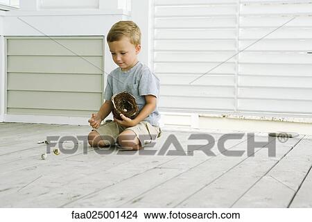 Picture - Boy kneeling on the ground, spilling eggs out of bird's nest. Fotosearch