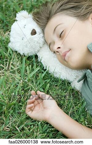 Boy lying in grass with eyes closed, head resting on teddy bear View Large Photo Image Stock Photo - Boy lying in grass with eyes closed, head resting on teddy bear. Fotosearch