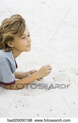 Boy lying in sand, looking away, side view View Large Photo Image Stock Photo - Boy lying in sand, looking away, side view. Fotosearch