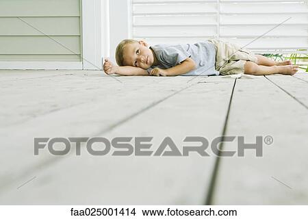 Picture - Boy lying on the ground next to starfish, head resting on arm. Fotosearch