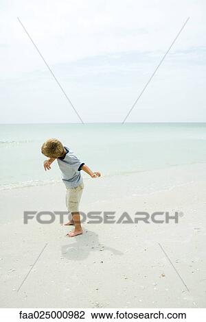 Boy on beach throwing rock toward ocean, full length View Large Photo Image Stock Image - Boy on beach throwing rock toward ocean, full length. Fotosearch