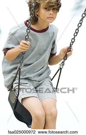 Boy on swing, looking at camera View Large Photo Image Stock Image - Boy on swing, looking at camera. Fotosearch
