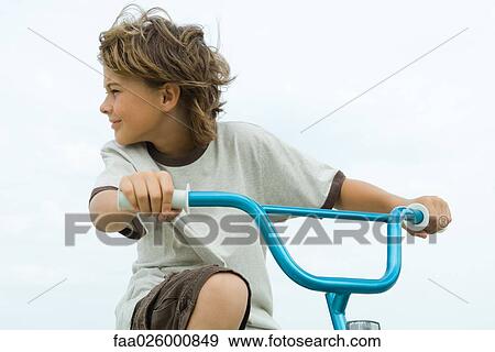 Boy riding bicycle, looking over shoulder, close-up View Large Photo Image Stock Photo - Boy riding bicycle, looking over shoulder, close-up. Fotosearch