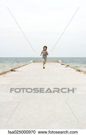 Boy running on pier, towards camera, ocean in background View Large Photo Image Stock Image - Boy running on pier, towards camera, ocean in background. Fotosearch