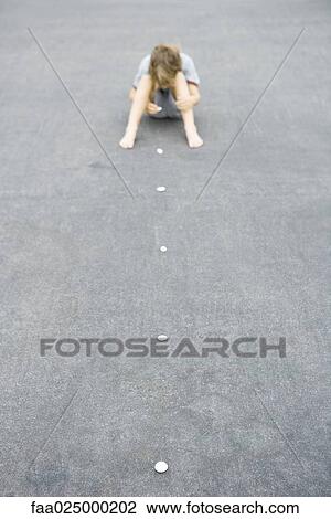 Boy sitting on the ground arranging line of pebbles, high angle view View Large Photo Image Stock Image - Boy sitting on the ground arranging line of pebbles, high angle view. Fotosearch