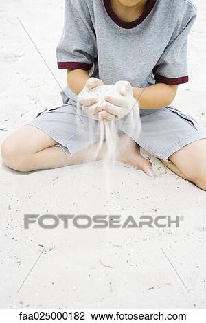 Boy sitting on the ground holding handful of sand, cropped view View Large Photo Image Stock Image - Boy sitting on the ground holding handful of sand, cropped view. Fotosearch