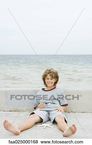 Boy sitting on the ground with starfish, smiling at camera View Large Photo Image Stock Photo - Boy sitting on the ground with starfish, smiling at camera. Fotosearch