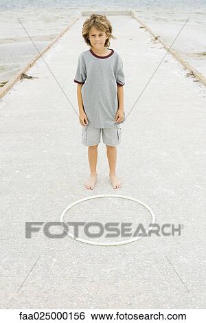 Boy standing on pier in front of plastic hoop, looking at camera and biting lip View Large Photo Image Stock Photograph - Boy standing on pier in front of plastic hoop, looking at camera and biting lip. Fotosearch