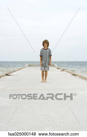 Boy standing on pier, looking at camera View Large Photo Image Stock Photo - Boy standing on pier, looking at camera. Fotosearch