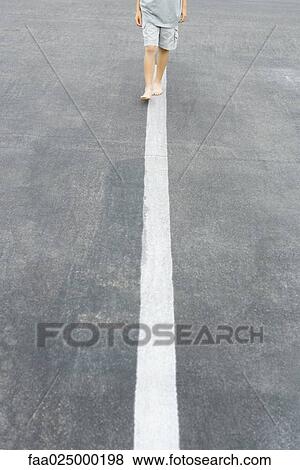 Boy walking along white dividing line, cropped view View Large Photo Image Stock Photo - Boy walking along white dividing line, cropped view. Fotosearch
