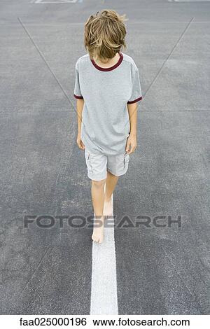 Boy walking along white dividing line, high angle view View Large Photo Image Stock Photograph - Boy walking along white dividing line, high angle view. Fotosearch