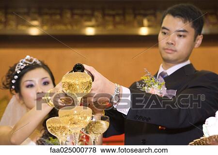 Bride and groom pouring champagne into stacked champagne glasses together View Large Photo Image Stock Photo - Bride and groom pouring champagne into stacked champagne glasses together. Fotosearch