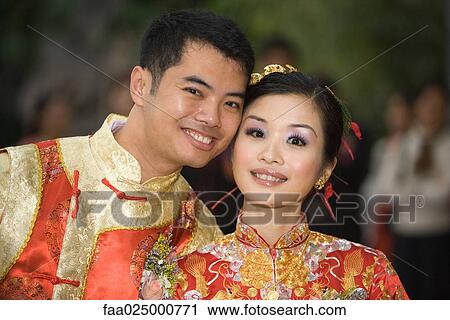 Bride and groom smiling at camera together, both dressed in traditional Chinese clothing View Large Photo Image Stock Image - Bride and groom smiling at camera together, both dressed in traditional Chinese clothing. Fotosearch
