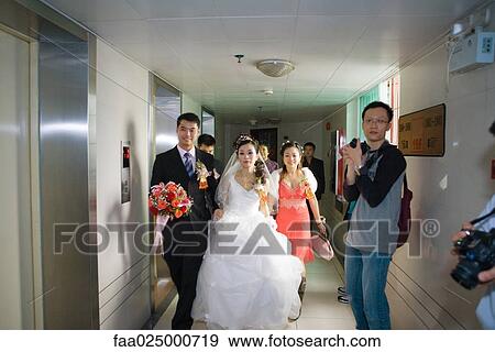 Bride and groom walking through hallway while photographers stand ready with cameras View Large Photo Image Stock Photo - Bride and groom walking through hallway while photographers stand ready with cameras. Fotosearch