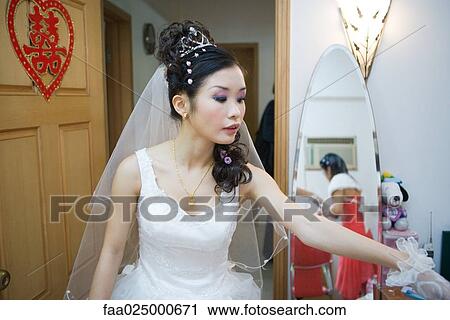 Stock Image - Bride in bedroom, Chinese character on door, looking away. Fotosearch